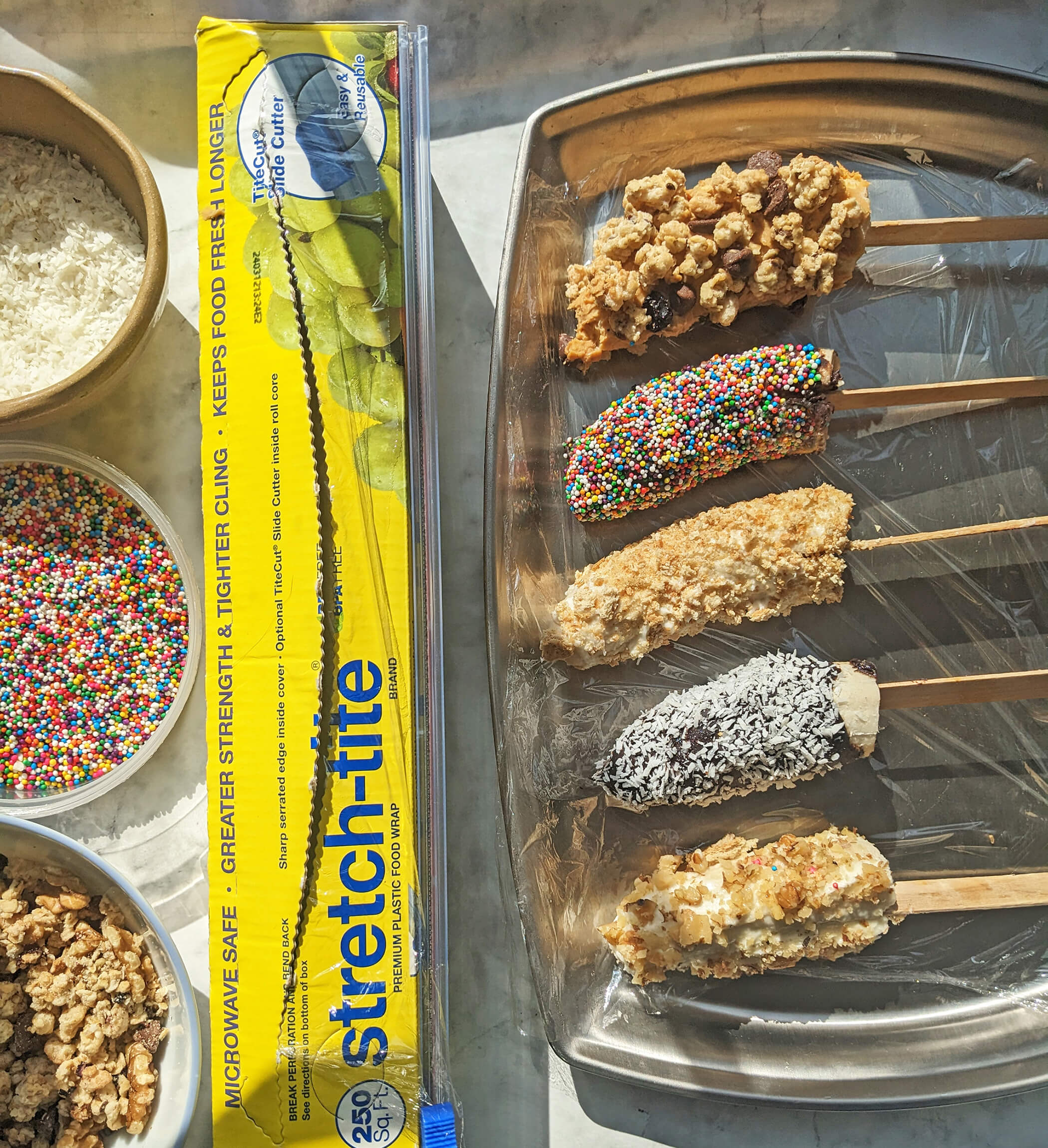 banana pops on tray with stretch-tite and toppings